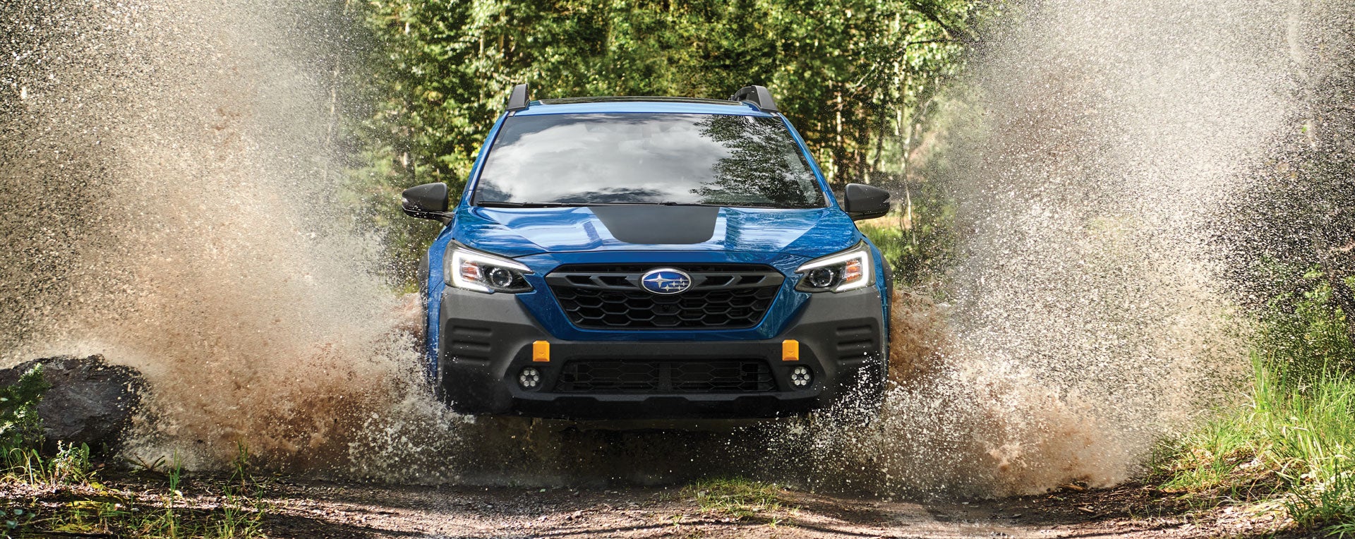 A 2023 Outback Wilderness driving on a muddy trail. | Subaru of Grand Blanc in Grand Blanc MI