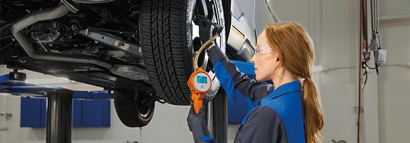 A Subaru technician checking tire pressure. | Subaru of Grand Blanc in Grand Blanc MI